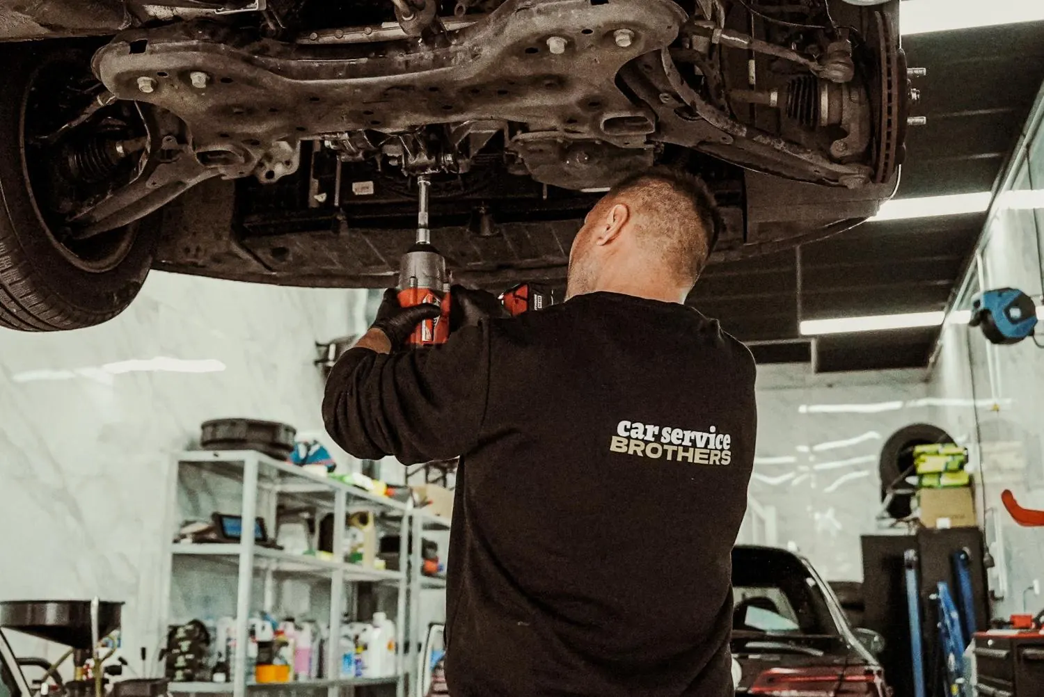 Monteur werkt onder een auto op de brug in de werkplaats van CarService Brothers