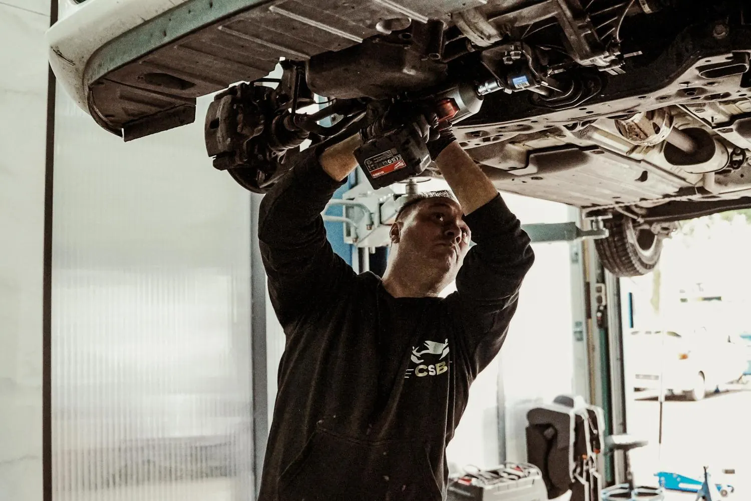Monteur van CarService Brothers aan het werk onder een auto